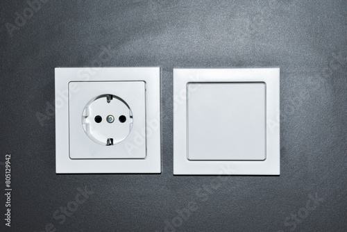 White electrical socket and switch on a gray wall