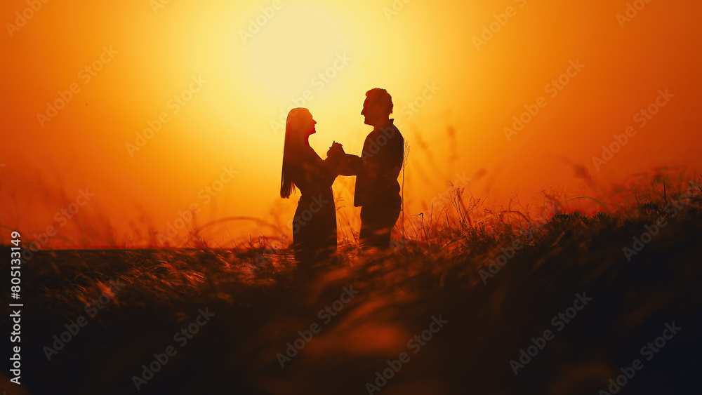 Sunset landscape with two lovers, a man and a woman. Beautiful nature in summer. Natural spikelets of grass developing in the wind. Sunset landscape with two lovers, a man and a woman. Beautiful nature in summer. Natural spikelets of grass developing in the wind.