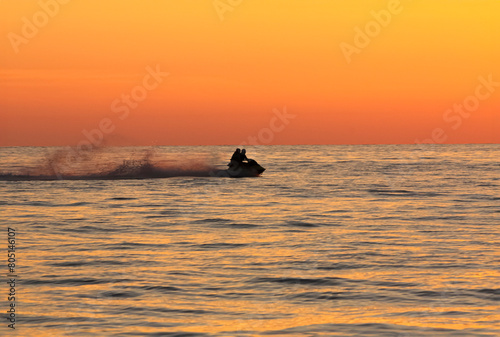 Sunset silhouette of a couple on a jet-ski in the sea © EyeMFlatBoard
