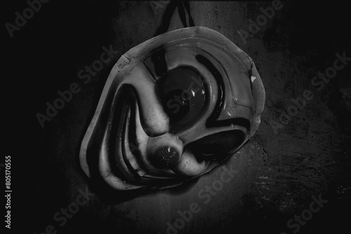 a clown mask hanging on the wall of a dark room