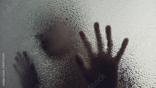 A woman behind the frosted glass puts her hand and face on the window surface photo