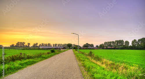 Sunset falls over an empty rural country road in the south of The Netherlands. Featuring a lonely street lantern. photo
