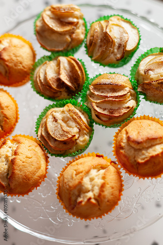 Delicious homemade vanilla muffins with sliced apple on the glass plate on white background. Sweet dessert for celebration, party or snack. Cupcakes.