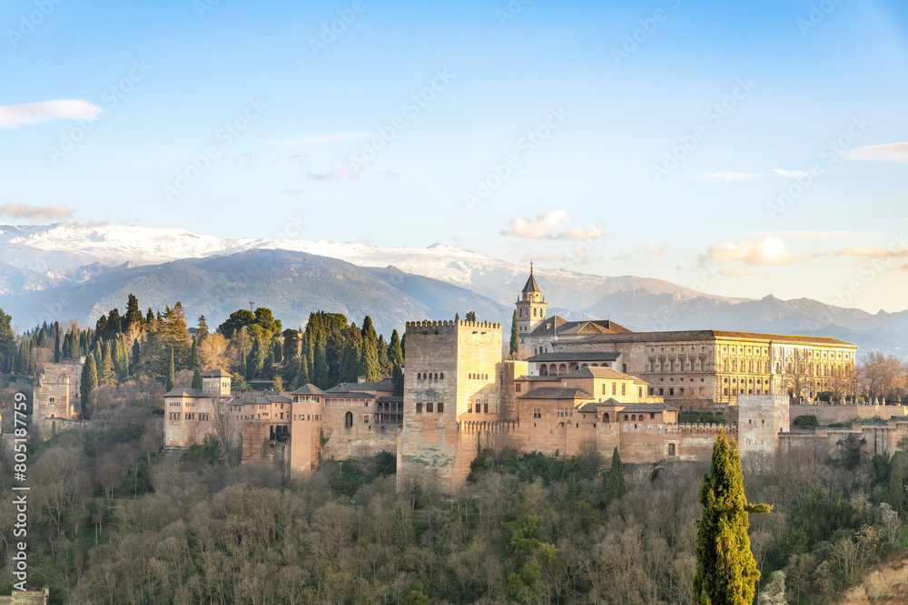High level panoramic sunset view over the Alhambra palace with Islamic and Spanish architecture in Granada, Spain and the snowcapped Sierra Nevada mountains in the background