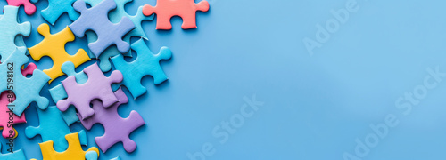 colorful jigsaw puzzle pieces isolated on wide blue background with space for text, Concept of Autism, alzheimer awareness, seizure disorder	