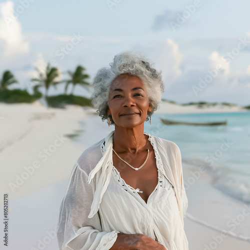 A woman with gray hair is smiling on a beach