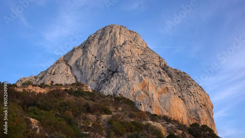 View of Peñón de Ifach mountain. Beautiful warm colours reflecting on the mountain peak at sunset. Natural Park in Calpe city, Alicante Province, Spain. Famous travel attraction, can be visited daily. photo