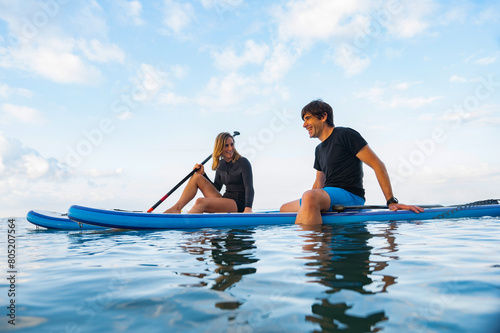Two young people having relaxation time practicing paddle surf