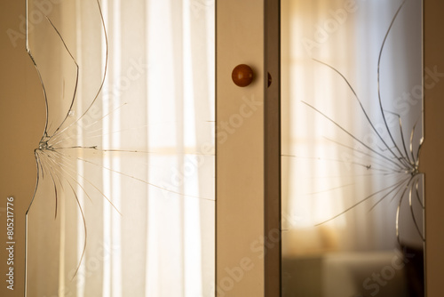 Broken mirrors on the wardrobe door. Reflection of the window and tulle curtain in the mirror. Male violence, violence against women, domestic violence concept.