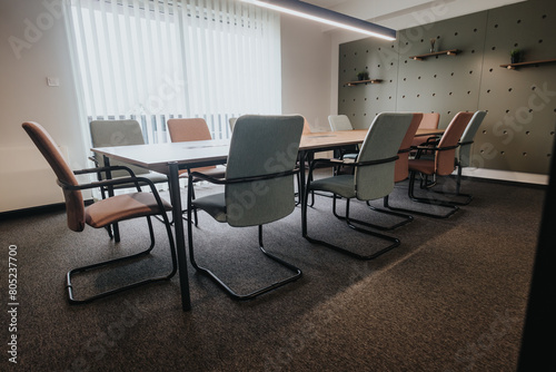 A well-equipped modern business meeting room, featuring stylish, comfortable chairs and practical conference table set under ambient lighting, ideal for professional gatherings.