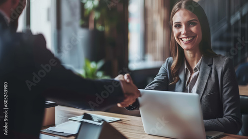 A happy middle-aged businesswoman manager shakes hands with a male client as a sign of concluding an agreement. Smiling female executive making a successful deal with a partner, shaking hands at work, photo