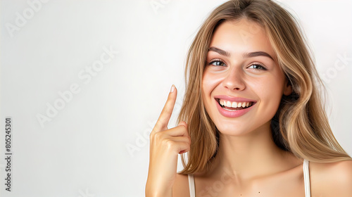 smiling pretty well-groomed young woman showing index finger up, isolated on white background, empty copy space