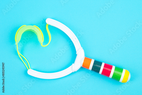 Children's plastic slingshot isolated on a blue background.
