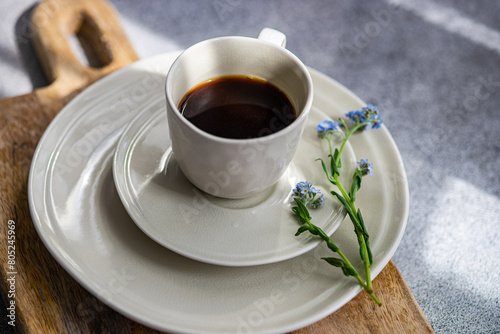 Close-up of a cup of black coffee with a forget-me-not flower