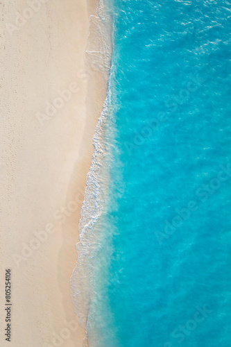 Summer seascape beautiful waves, blue sea water in sunny day. Top view from drone. Sea aerial surf, amazing tropical nature background. Mediterranean bright sea bay, waves splashing beach sandy coast