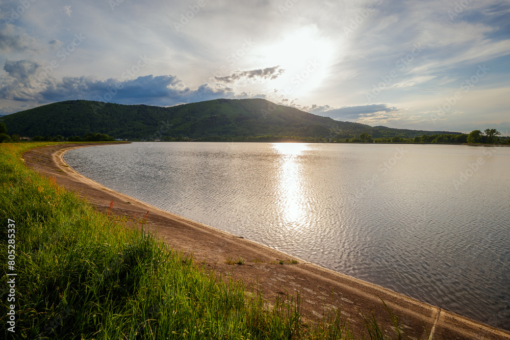 Sunset over Lake Czanieckie in Porąbka. Spring in the Beskid Mały Mountains. The bridge in the distance. A fragment of the blue tourist trail