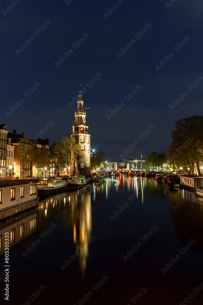 The Montelbaanstoren tower in Amsterdam reflecting in the waters of the Oudenschans canal at night