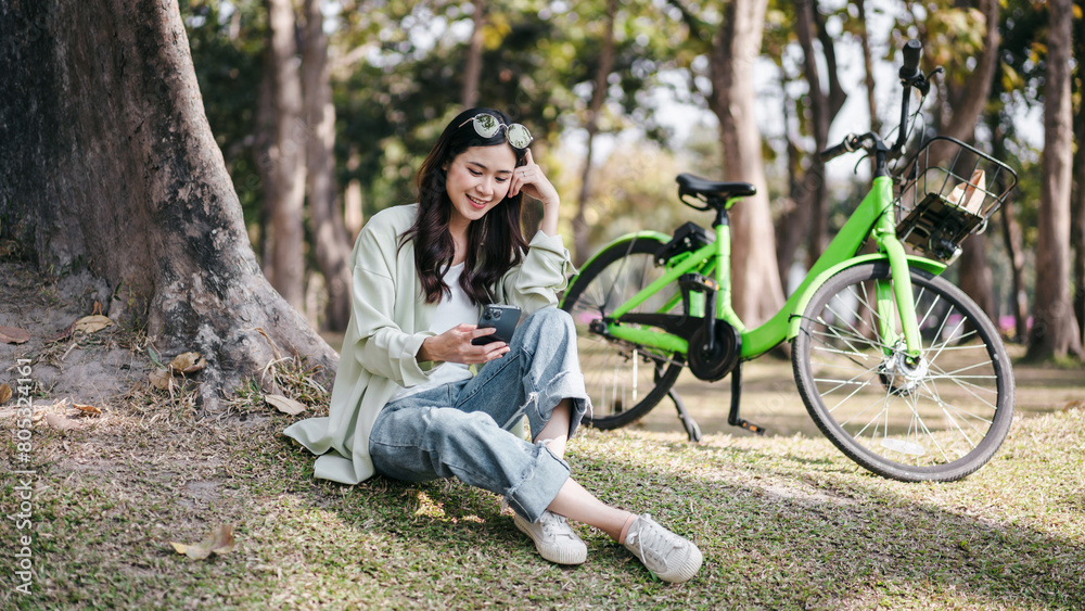 A woman is sitting on the grass next to a green bicycle A woman is sitting on the grass next to a green bicycle