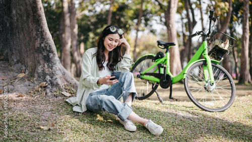 A woman is sitting on the grass next to a green bicycle