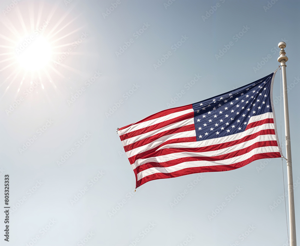 Obraz premium A large American flag waving in the wind against a bright, cloudy sky