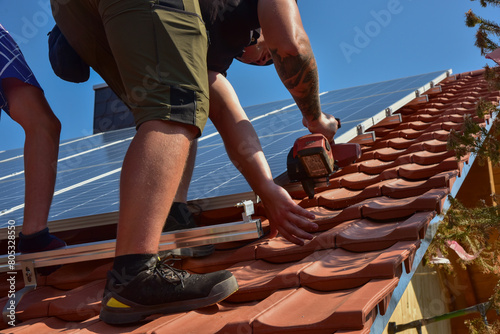 Dachdecker beim Aufbau einer Photovoltaikanlage auf einem neu gedeckten Ziegeldach: Kürzen der Schienen mit der Trennscheibe an der Position der Endklemme