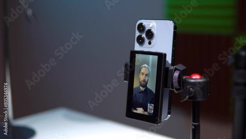 a young man film video of himself on the phone and displays the video on the monitor screen