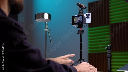 a young man film video of himself on the phone and displays the video on the monitor screen