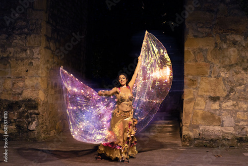 Belly dancer with wings of light under a starry sky	