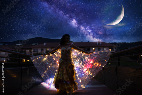 Belly dancer with wings of light under a starry sky	