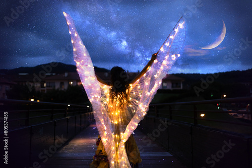 Belly dancer with wings of light under a starry sky	