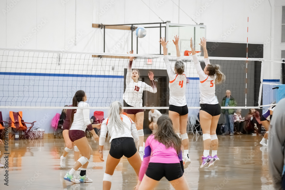 Female college volleyball player rolls the ball over the block