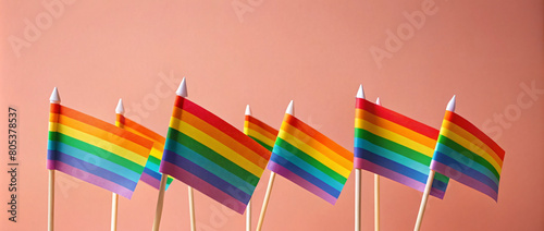 A group of bright colored rainbow flags in red, yellow, blue and green flutters against a background
