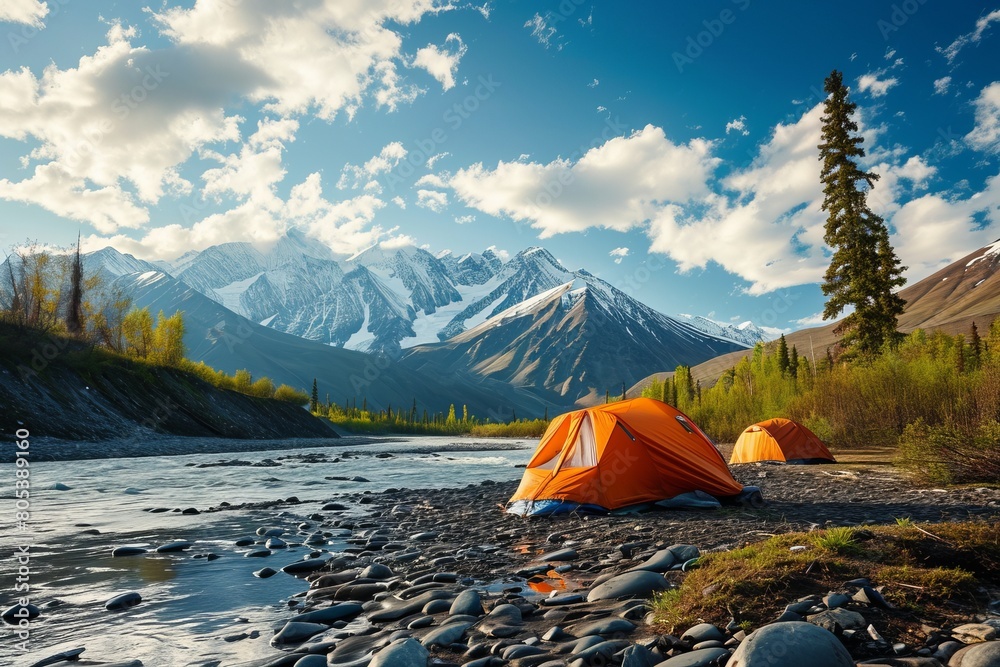 Bright tents in a tent campsite in the forest on the river bank against the backdrop of the mountains. Concept of tourism, vacation, travel, hiking
