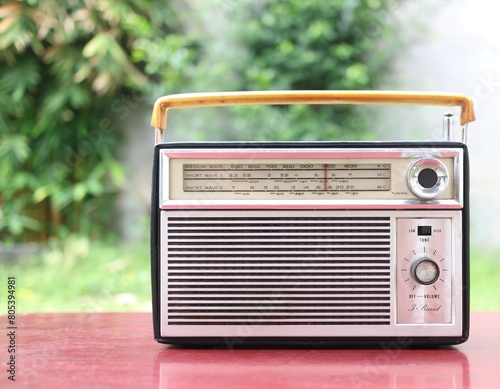 vintage silver transistor radio on wooden table backyard background