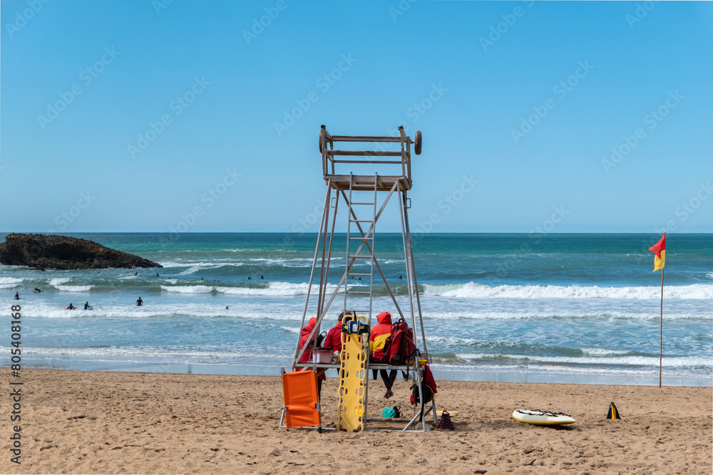 Torre de vigilância com alguns socorristas a garantirem a segurança dos banhistas e surfistas que desfrutam das ondas Torre de vigilância com alguns socorristas a garantirem a segurança dos banhistas e surfistas que desfrutam das ondas
