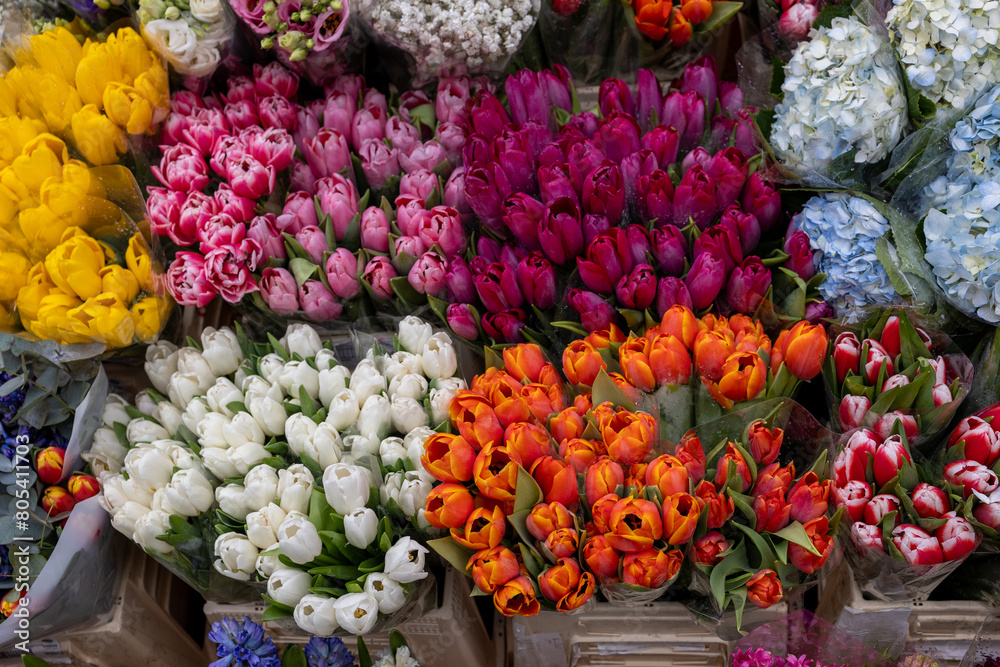 Colorful flowers stacked on table for flower arranging in city market.