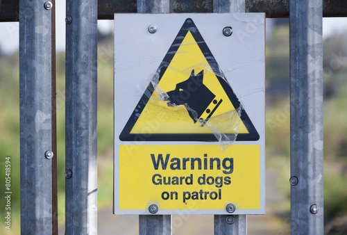 Guard dogs on patrol warning sign on security fence at construction site