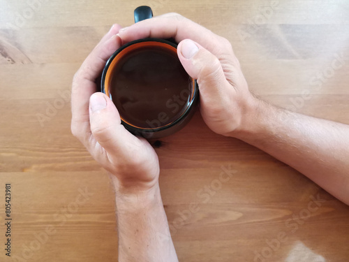 Cup of black tea in the hand of men . on a wooden background