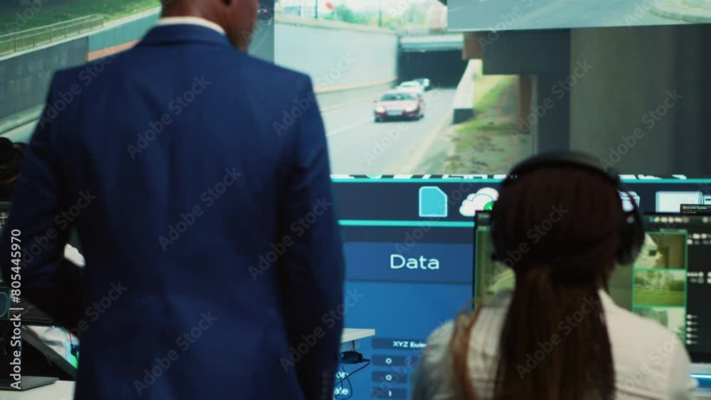 Supervisor arriving in the control center at shipping agency, overseeing main gps locating activities to ensure order and parcel delivery. Diverse employees working with satellite maps. Camera A.