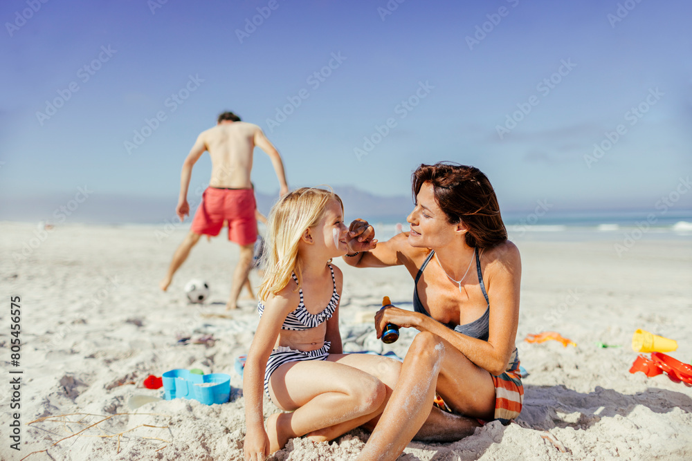Mother applying sunscreen to daughter on a sunny beach day Mother applying sunscreen to daughter on a sunny beach day