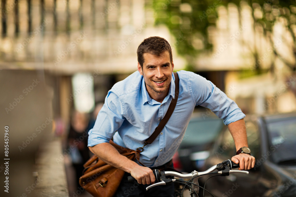 Smiling young businessman riding a bicycle in city Smiling young businessman riding a bicycle in city