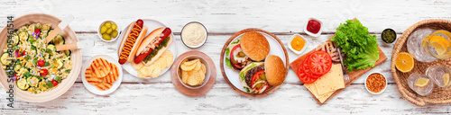 Photography Summer BBQ or picnic table scene with hamburgers, hotdogs, salad and snacks