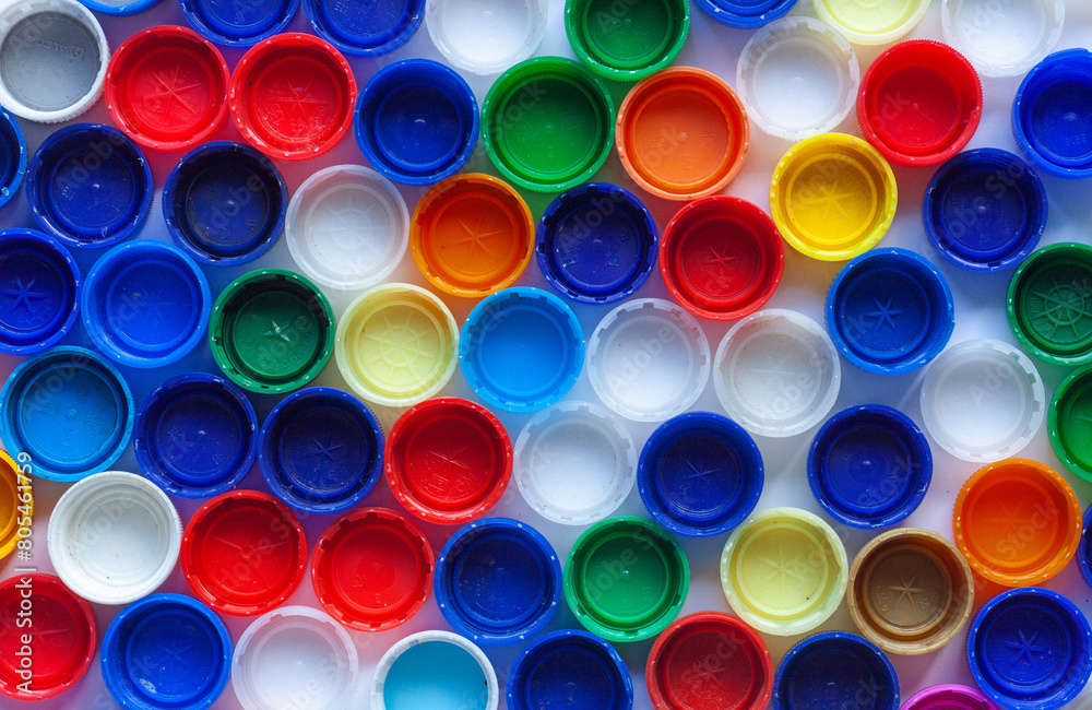 Abstract full frame background made of a lot of plastic bottle caps or lids in bright colors red, blue, green, yellow, white, orange regular surface