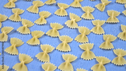 IItalian uncooked white pasta in the form of bows are laid out in rows on light blue fabric, natural decorative background photo