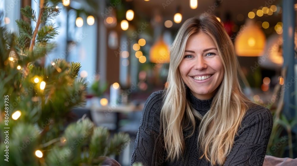 A woman seated at a table before a Christmas tree, lit walls behind A woman seated at a table before a Christmas tree, lit walls behind