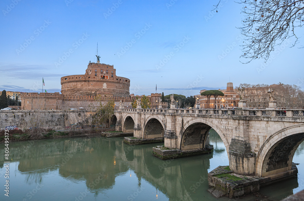 Obraz premium A grand bridge stretches across a tranquil river, leading to a majestic castle nestled in the background. The bridges intricate architecture contrasts against the serene water and lush surroundings