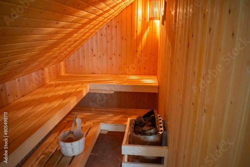 Gemütliche Sauna mit Saunaofen und Hölzernerm Saunakübel mit Holzkelle in warmen Licht. photo