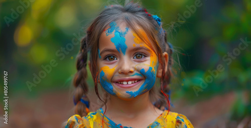 A young girl wearing a bright color shirt  shows her hands and palms painted in vibrant color in the Holi or Colors Festival isolated on a colorful background.