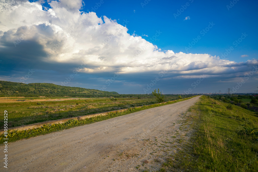 unpaved road with blue sky with clouds.