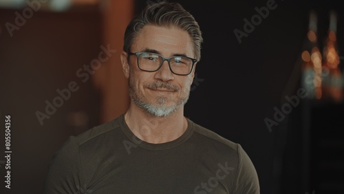 Portrait of smiling mature man with grey hair and glasses in casual at home. Happy middle aged, older male in 50s with friendly and confident smile. Blank copy space for text.